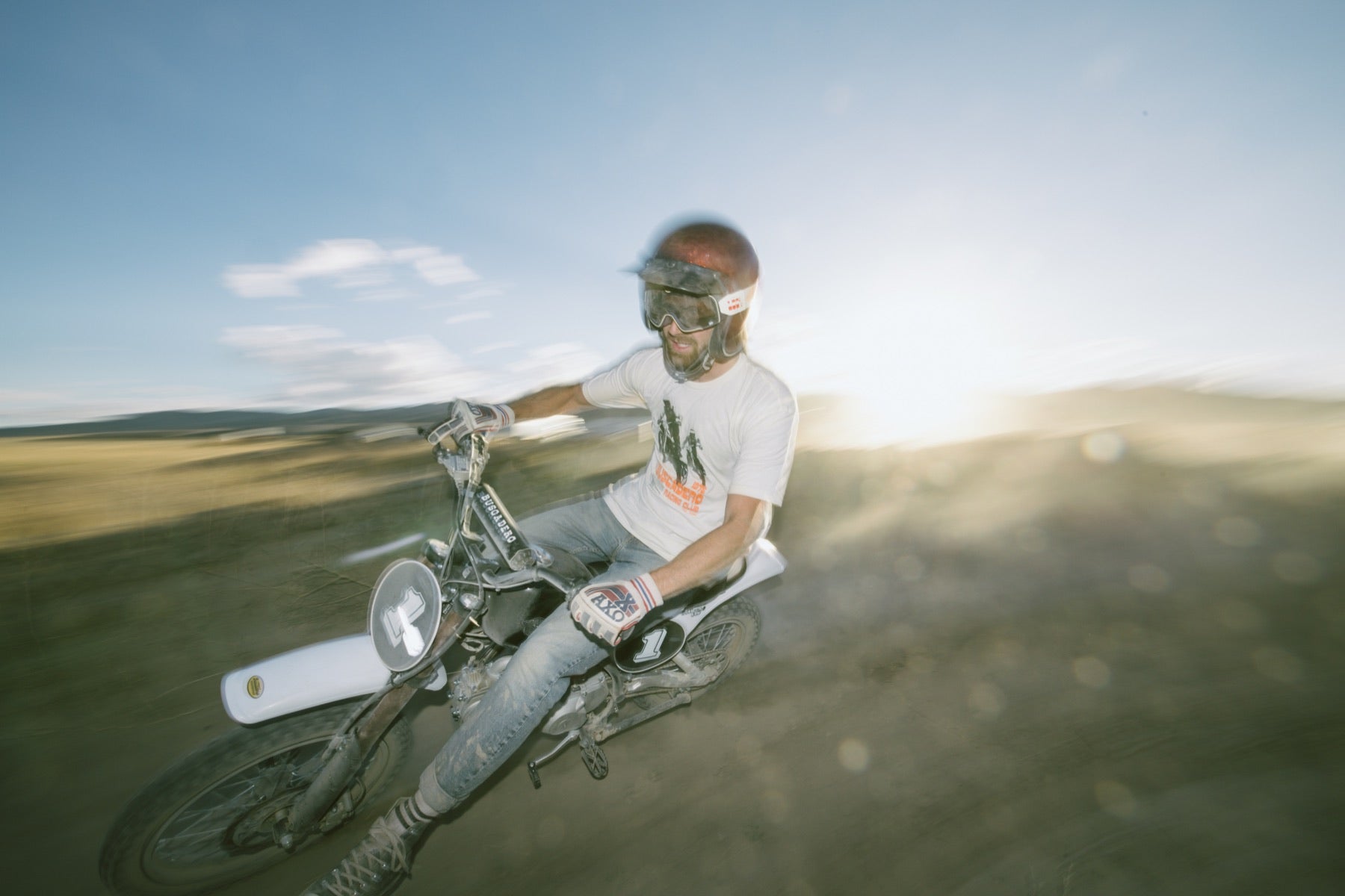 Smiling rider on a white-tank BSX 110 with the sun behind him