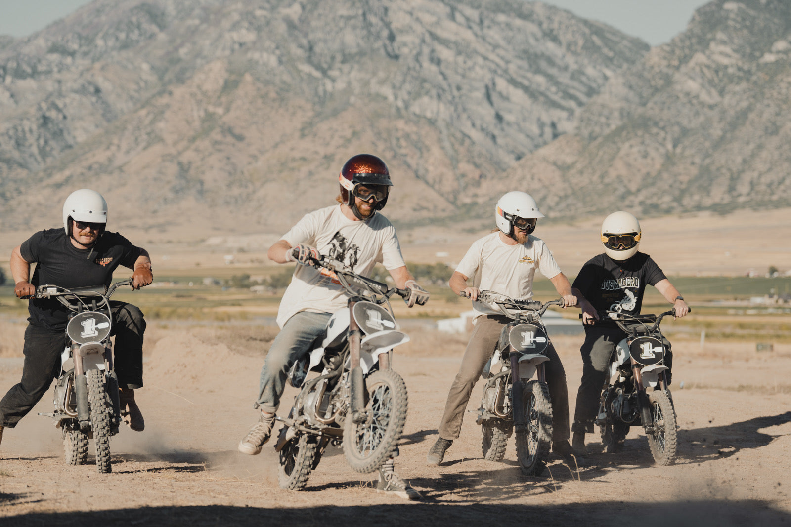 Friends smiling and riding together on white-tank BSX 110 and black-tank BSX 140 pit bikes